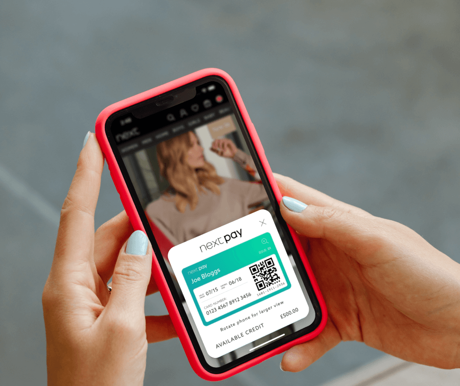 A person's hands holding a phone displaying the Next Pay credit overlay