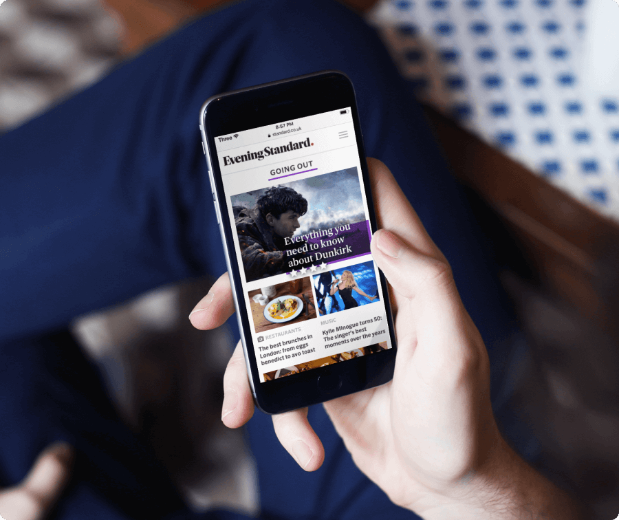 A person's hands holding a phone displaying the Evening Standard mobile website